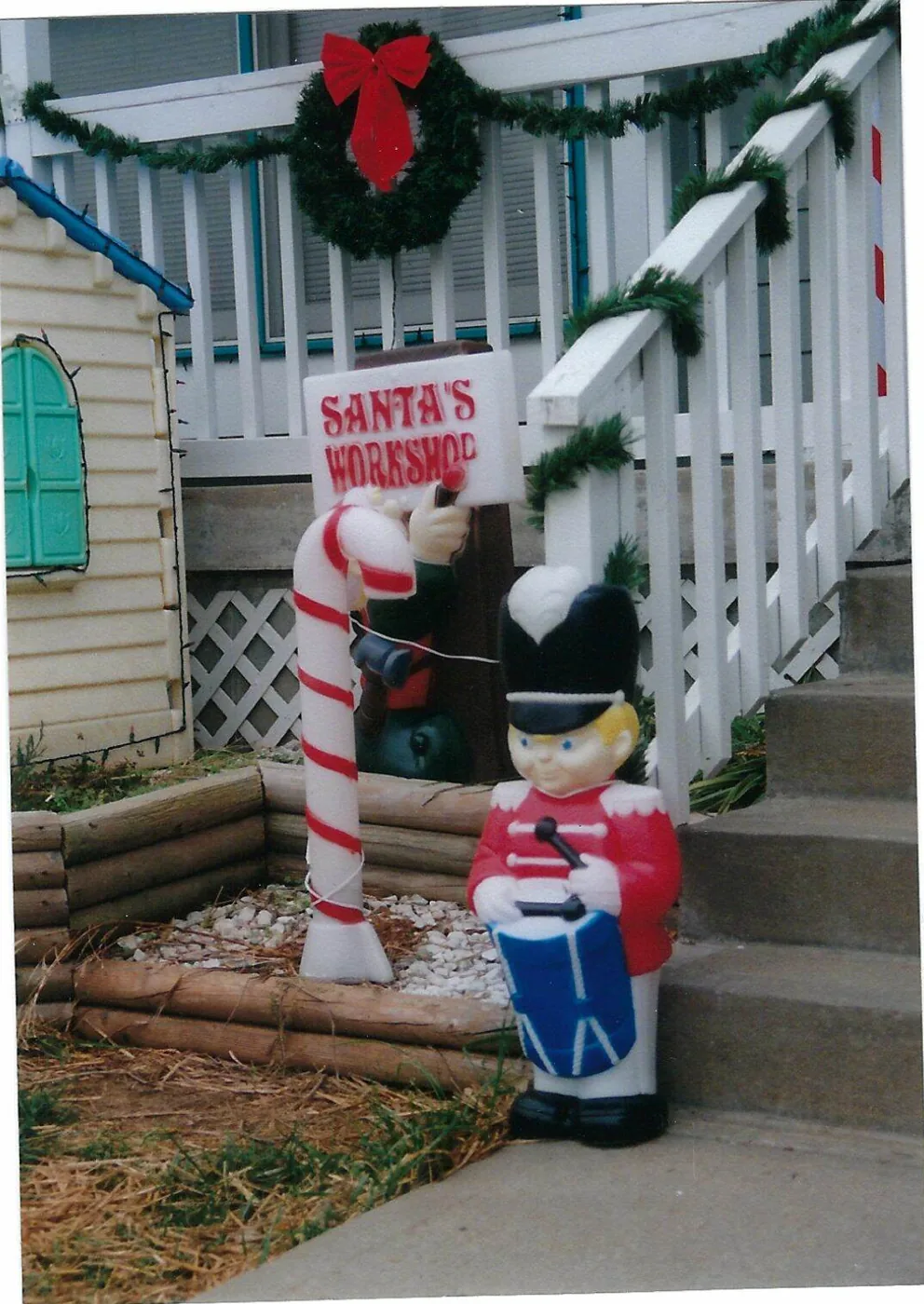 A toy soldier blow mold beside a Santa's Workshop sign on the front steps in 2006