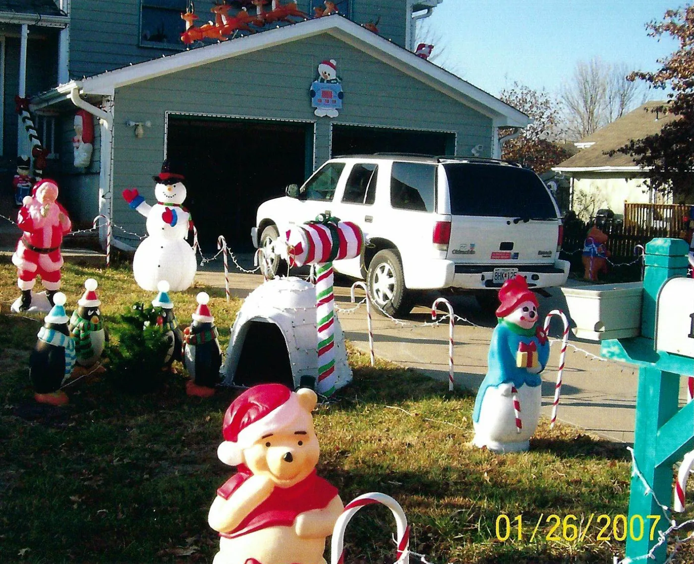 A bear in a Santa hat, snowmen, and candy canes along the drive